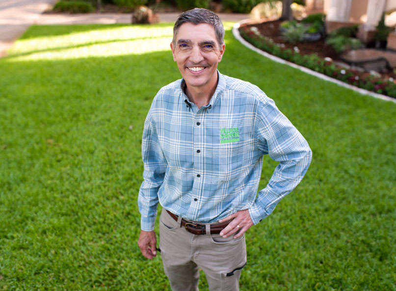Ken Hyatt, owner and founder of Village Green Lawn and Pest, standing on a healthy green lawn at a North Texas home